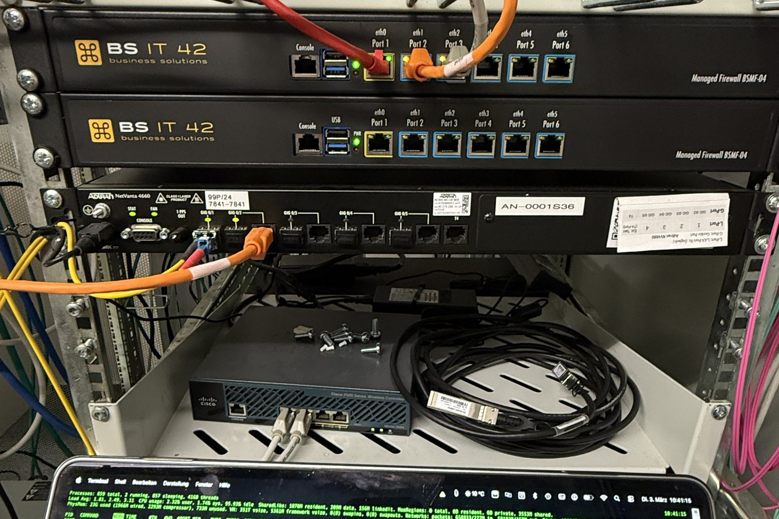 Zwei eingebaute Managed Firewalls BSMF-04 im Schrank, daneben ein Notebook mit laufender Systemanzeige